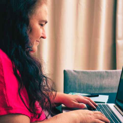 Autorin Anke O'Brien sitzt am Tisch und schreibt an ihrem Laptop.